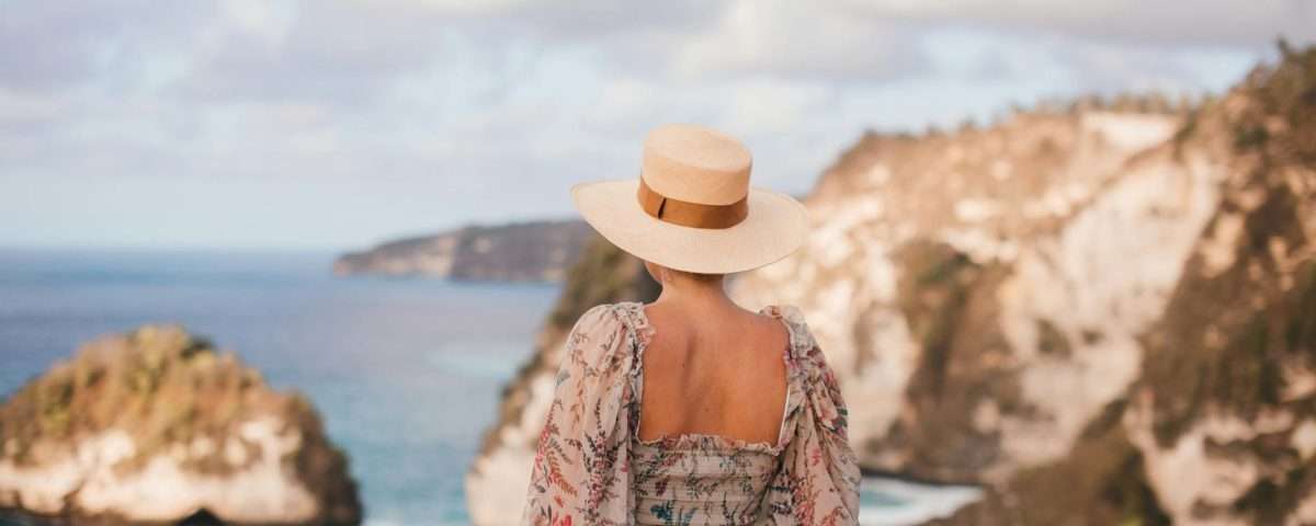 trendy woman in hat admiring rocky cliffs