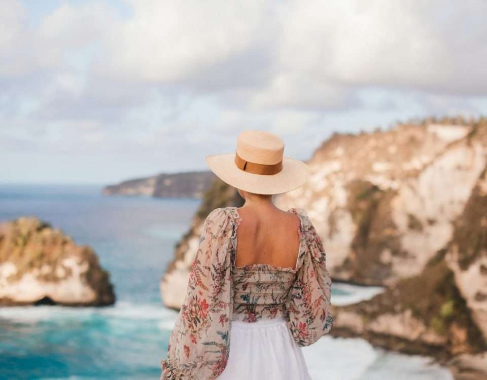 trendy woman in hat admiring rocky cliffs